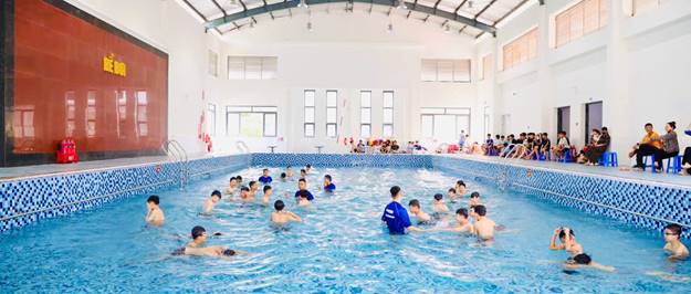 Các em học sinh được HLV hướng dẫn các kỹ năng bơi cơ bản